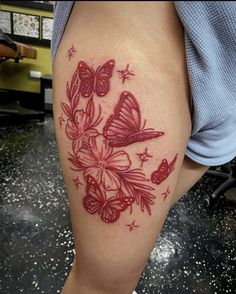 a woman's thigh with butterflies and stars tattoo on her leg, which is red