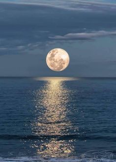 the full moon shines brightly in the sky over the ocean as it reflects on the water