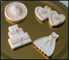 wedding cookies are arranged on top of a gold platter with white and pink decorations