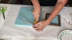 a person cutting paper on top of a table with scissors and other crafting supplies