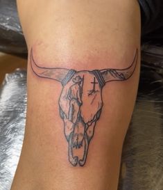 a tattoo on the leg of a woman with a cow skull and cross in it