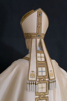 the back of a priest's white robe with gold and blue accents on it