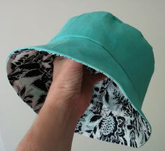 a person holding up a green hat with black and white designs on the brim