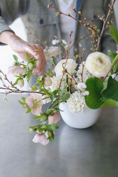 a person arranging flowers in a vase on a table