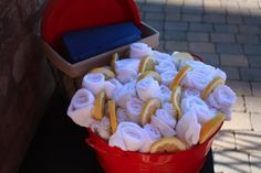 a red bucket filled with lots of lemons next to a brick wall and sidewalk