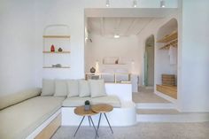 a living room filled with furniture and shelves on the wall next to a white couch