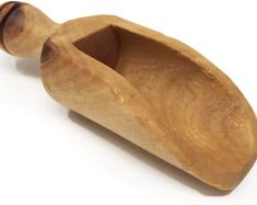 a wooden boat shaped like a spoon on a white surface with the handle extended up