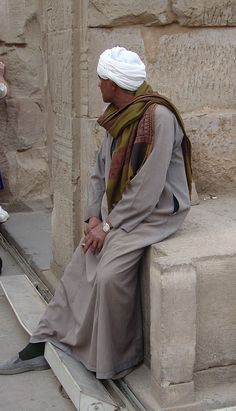 an old man sitting on the side of a building