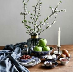 an arrangement of food on a table with flowers in a vase and candlesticks