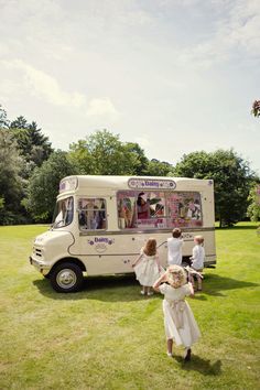 people are standing in front of an ice cream truck that is parked on the grass