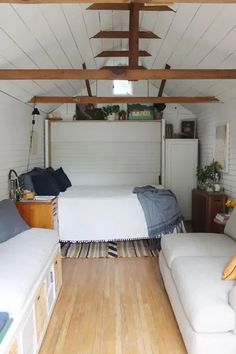 a bed sitting inside of a bedroom on top of a hard wood floor next to a white couch