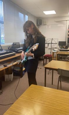 a woman is playing an electric guitar in a room full of desks