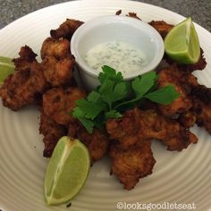 a white plate topped with tater tots covered in sauce and garnished with cilantro