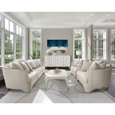 a living room filled with white furniture and large windowed windows on the side of it