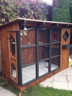 a large wooden structure with many cages on it's sides in the grass next to a house