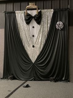 a black and white backdrop with a bow tie hanging on it's side in front of a wall