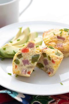 an omelet on a white plate with sliced avocado next to it