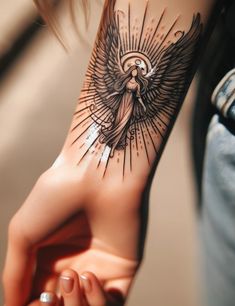 a woman's arm with an angel tattoo on it, holding her hand out to the side