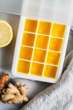 the ingredients to make ginger ice cubes are displayed on a white plate, next to an orange slice