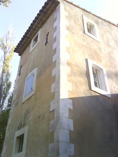 a tall building with two windows and a clock at the top of it's side