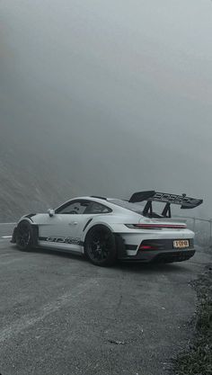 a white sports car parked on the side of a road in front of a mountain