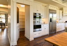 a large kitchen with white cabinets and stainless steel appliances in an open floor plan area