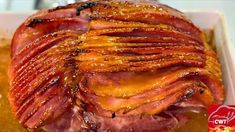 ham wrapped in bacon sitting on top of a pan filled with sauce and seasoning