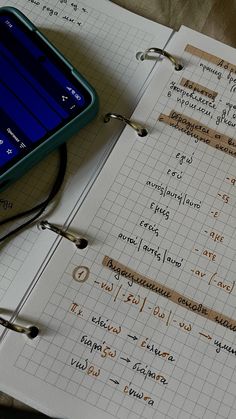 a cell phone sitting on top of an open notebook next to a pen and calculator