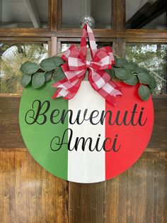 a sign that says beneweuti amici hanging on a door with a bow