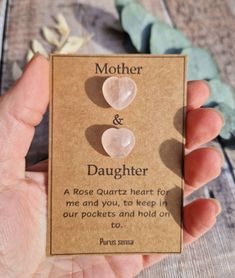 a person holding up a card with two heart shaped stones on it's back