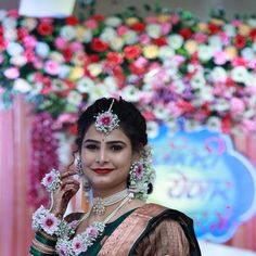 a woman in a green and gold sari holding a cell phone to her ear