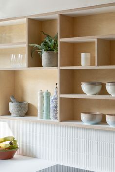 the shelves have bowls, cups and vases on them