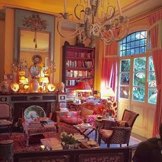 a living room filled with lots of furniture and a chandelier hanging from the ceiling