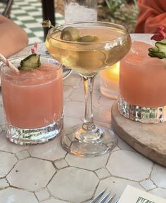 two glasses filled with drinks sitting on top of a table