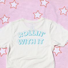 Rollin' With It Tee Light Blue Graphic Print Relaxed Fit T-shirt, Light Blue Cotton T-shirt With Graphic Print, Trendy Light Blue Graphic Print T-shirt, Fun Unisex T-shirt With Screen Print, Light Blue Graphic Print T-shirt, Light Blue Graphic Print T-shirt With Relaxed Fit, Light Blue Relaxed Fit T-shirt With Text Print, Relaxed Fit Light Blue T-shirt With Text Print, Fun Cotton T-shirt With Screen Print