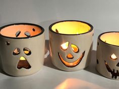 three halloween candles with faces on them sitting next to each other in front of a white background