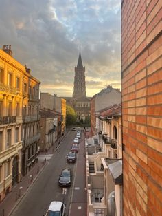 cars are parked on the street in front of some buildings and a church steeple