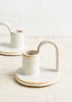 two white cups and saucers sitting on top of a table