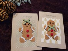 two christmas cards with gingerbreads on them next to a pine cone and plant