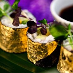 three gold foiled sushi rolls with black olives and garnishes