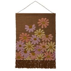 a brown wall hanging with pink and yellow flowers on the front, fringes in the back