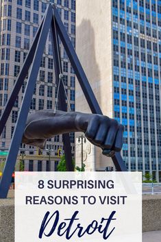 a statue with the words 8 surprising reasons to visit detroit in front of skyscrapers