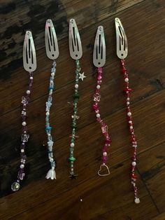 five different colored beads and silverware on a wooden table with one bead in the middle