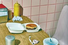 a wooden table topped with plates and containers filled with food next to a trash can