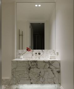 a bathroom with a marble counter top and white walls, along with a large mirror above the sink