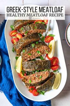 greek - style meatloaf with tomatoes, lettuce and lemons on a white platter