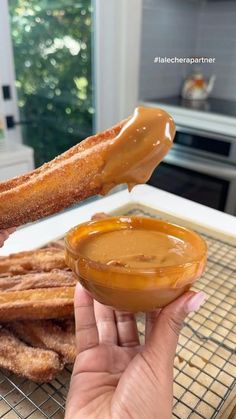 someone is dipping some kind of sauce in a bowl on top of churros