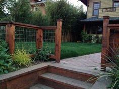 a wooden fence sitting next to a lush green yard on top of a stone walkway