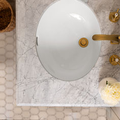 a white sink sitting on top of a bathroom counter next to a vase with flowers