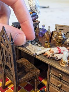 a miniature desk with an open drawer and small dollhouse furniture on it's side